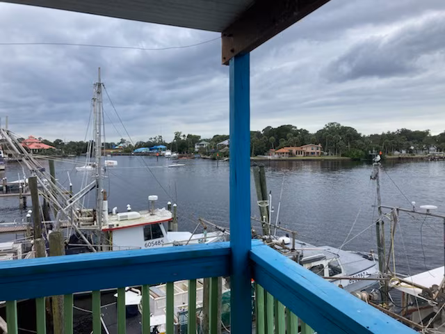 The view from the restaurant's second-story balcony overlooking the commercial marina filled with fishing boats, showcasing the property's waterfront amenities.